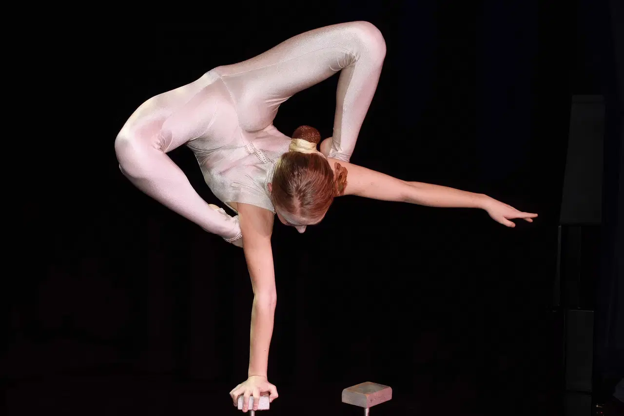 Contortionist in a silver bodysuit holding a handstand