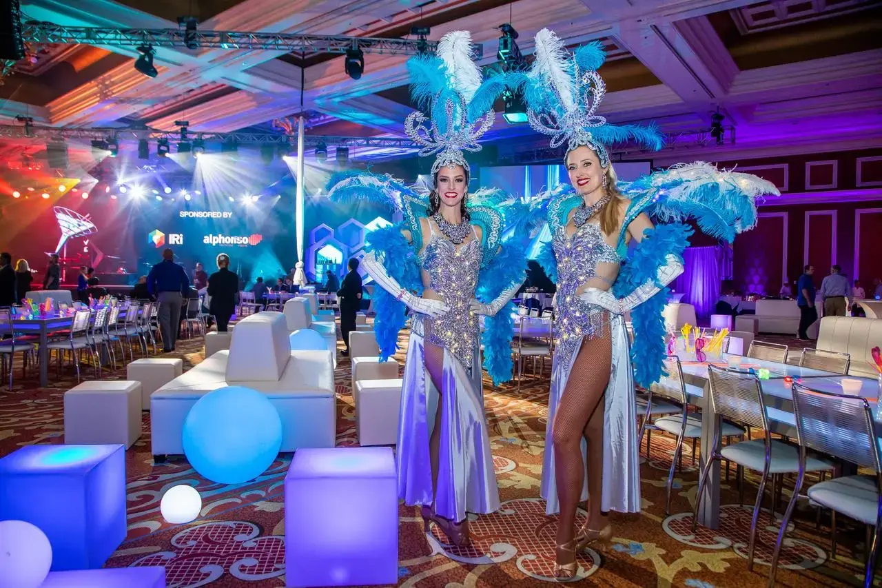 Las Vegas showgirls in blue and silver costumes at a corporate event
