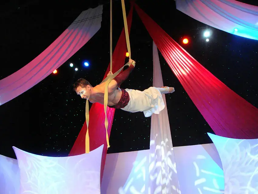 Male aerialist performing on yellow silks