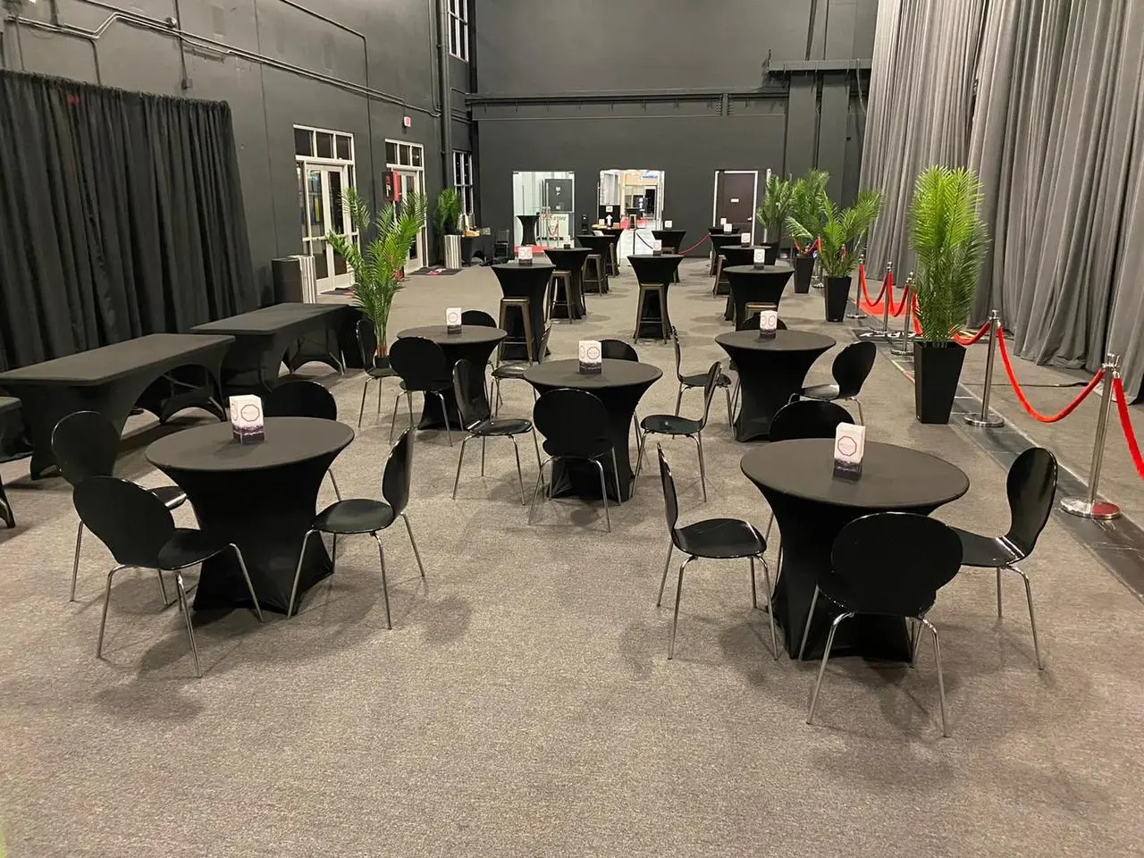 Indoor event black tables chairs green plants for rent in Las Vegas