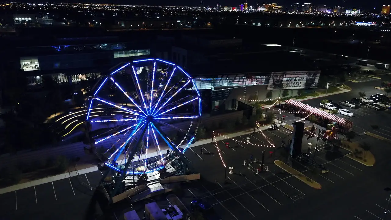 Aerial night view of event tents and a ferris wheel against the Las Vegas skyline