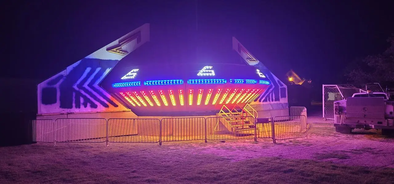 Night carnival spinning ride led lights yellow blue red patterns grassy field for rent in Las Vegas
