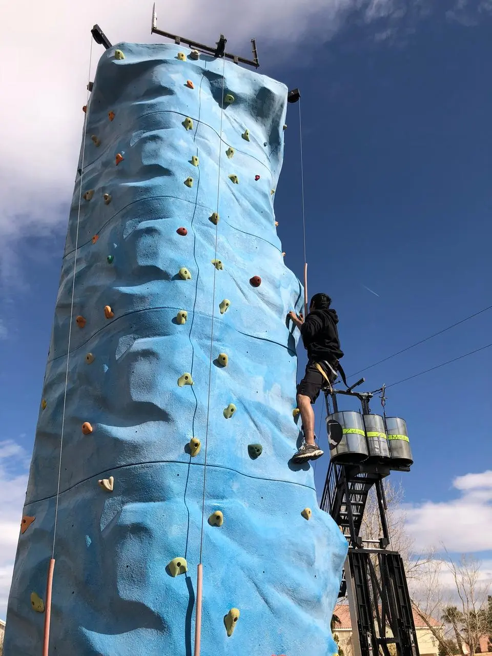 Rock climbing wall outdoor event blue wall colored handholds climber for rent in Las Vegas